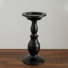 a black candle holder sitting on top of a wooden table