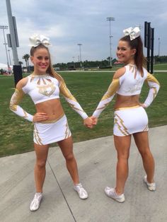 two cheerleaders holding hands and posing for the camera