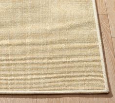 a beige area rug on the floor with wood floors and white walls in the background