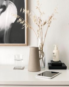 a vase with some flowers on a table next to a phone and water glass in front of it