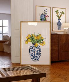 three framed pictures with flowers in them on a table next to a chair and sideboard