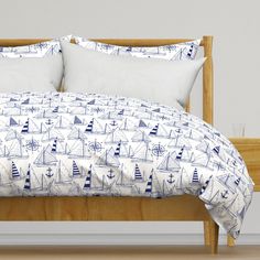 a bed with blue and white sailboats printed on the comforter, along with two pillows