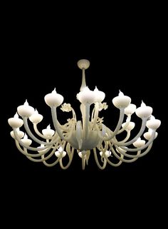 a white chandelier hanging from the ceiling in front of a black background,