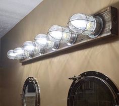 a row of lights sitting on the side of a wall above two mirrors in a bathroom