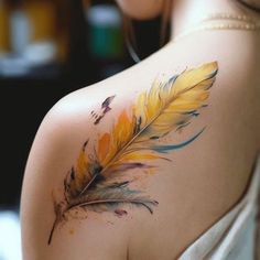 a woman's back with a yellow and blue feather tattoo on her shoulder