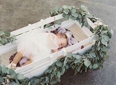 a baby is laying in a white box with greenery around it's sides