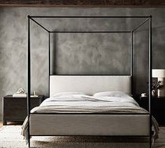 a four poster bed with white sheets and pillows in a room that has gray walls