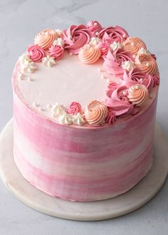 a pink and white striped cake with flowers on the top is sitting on a plate