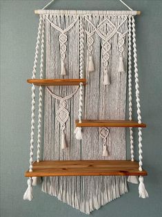 a macrame wall hanging with wooden shelves and tassels