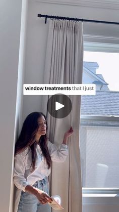 a woman standing in front of a window with curtains pulled back and the words window treatments that just come out