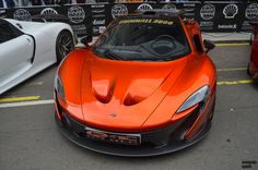 an orange sports car parked next to other cars