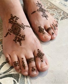 two feet with hendi tattoos on them, one is decorated with beads and the other has