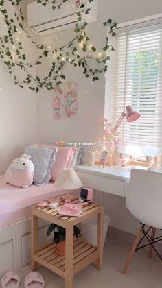 a room with a bed, desk and window covered in green vines hanging from the ceiling