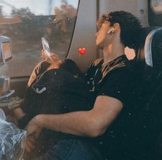 two people sitting on a bus looking at their phones