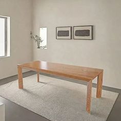 a wooden table sitting in the middle of a room next to two pictures on the wall