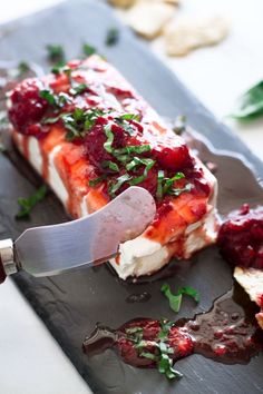 someone is cutting up some food on a black plate with a knife in it and garnishes around the edges