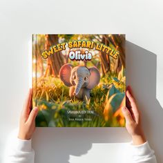 a person holding up a book with an elephant on it's cover in front of a white background