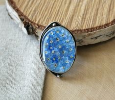 ✿ Adjustable antique Silver Plated Ring with real dried Forget me not flowers. ✿ SIZE: - Bezel size is 30x22 mm (1 3/16 x 7/8 inch)  - Depth of the bezel is 5 mm (7/32 inches) - Weight of the ring is 15 grams. ✿ Ring is oxidized silver plated Brass. Ring is adjustable. ✿ Only genuine dried mushrooms and plants where used in the process of making this piece, as well as all other items in this shop. ✿ Every piece in this shop was made in several casting steps, sanded and polished by hand. ✿ This item was made using special Eco resin, which is crystal clear, UV stable, doesn't have any smell to it and is absolutely safe for your health. ✿ ✿ Resin is a very strong material and, in contrast to glass, it can not break! ✿ ✿ All items are shipped in a GIFT BOX, you don't have to pay extra for the Forget Me Not Ring, Forget Me Not Flowers, Dried Mushrooms, Jewelry Real, Flowers Dried, Eco Resin, Floral Ring, Flower Jewelry, Forget Me Not