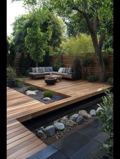 an outdoor living area with wooden decking and stone seating areas, surrounded by greenery