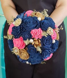 a bridal bouquet with blue, pink and gold flowers is held by a woman