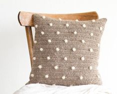 a crocheted pillow sitting on top of a bed next to a wooden chair