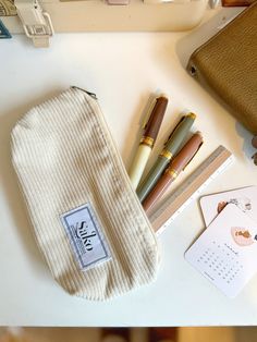 the contents of a purse sitting on top of a white table next to a wallet