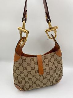 A stunning vintage Gucci Jackie bag made from beige canvas with tan leather trim and chunky gold hardware. This bag also has the iconic Gucci pin lock closure. Inside the bag is lined with a brown cotton lining and there is a zipped pocket for valuables. This bag is in very good vintage condition, there are some minor marks to the hardware and some minor signs of wear to the leather corners on base. A true collectors item and comes with its original Gucci dust bag. Vintage Gucci Jackie, Pin Lock, Diaper Backpack, Vuitton Bag, Casual Backpack, Baby Bag, Handbag Backpack, Leather Trim, Gucci Jackie Bag