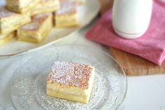 some desserts are sitting on glass plates next to a cup and plate with powdered sugar