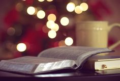 an open book sitting on top of a table next to a cup