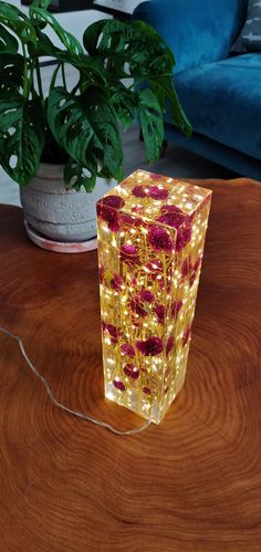 a glass vase sitting on top of a wooden table next to a potted plant