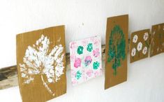 four pieces of cardboard are hanging on the wall with flowers and leaves painted on them