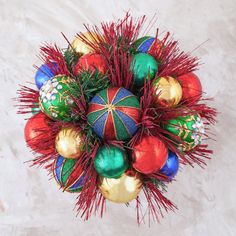 an overhead view of christmas ornaments on a white tablecloth with red, green and gold tinsel