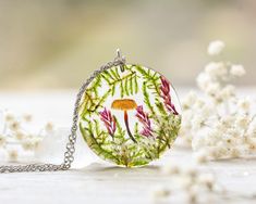 a glass pendant with an image of a flower on it sitting next to some white flowers