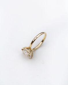 a gold ring with a single diamond on the front and side, against a white background