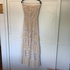 a dress hanging on a door with a hanger in front of it that has a white lace pattern