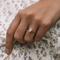 a close up of a person's hand with a diamond ring on their finger