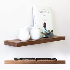 a book on a shelf next to two mugs