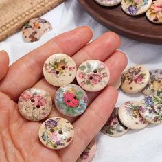 a person is holding some buttons in their hand and there are many flowers on them