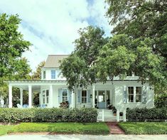 a white house with trees and bushes around it