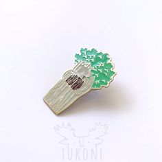 a green and white brooch with a tree on it