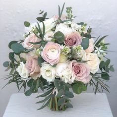 a bouquet of white and pink flowers sitting on top of a table