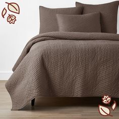 a bed with brown bedspreads and leaves on the wall behind it in a bedroom