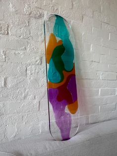 a glass vase sitting on top of a white couch next to a brick wall with an abstract painting