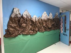 a bulletin board with mountains on it in an office hallway, painted blue and green