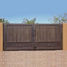 an iron gate with wooden slats on the top and bottom, in front of a tan stucco wall