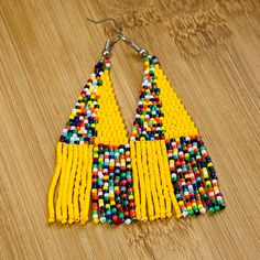 These African Maasai Zulu Style inspired Tribal earrings are definitely a standout. If you love African jewelry styles and these statement earrings, these are your earrings. Yellow Beaded Earrings With Ear Wire For Festivals, Yellow Beaded Drop Earrings For Festival, Bohemian Yellow Drop Earrings, Yellow Hoop Earrings With Dangling Beads, Yellow Single Dangle Earring, Single Yellow Dangle Earring, Yellow Handmade Tassel Earrings, Handmade Yellow Dangle Tassel Earrings, Yellow Festival Beaded Earrings