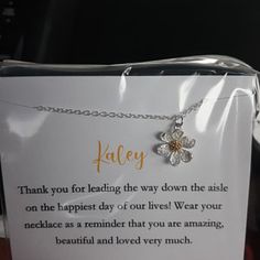 a white card with a silver flower on it and a note attached to the back