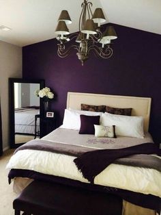 a large bed sitting under a chandelier next to a purple and white wall