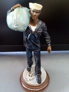 a figurine of a man holding a bag on top of a table next to a black wall