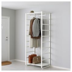 a white coat rack with two coats and purses hanging on the wall next to it